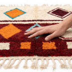 Ruby Horizon Azilal rug — hand resting on the soft wool pile
